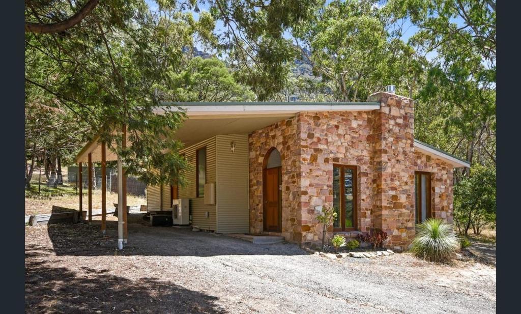 a small brick house in the middle of trees at Halls Gap House in Halls Gap