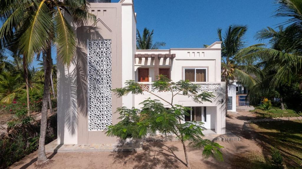 a white house with palm trees in front of it at Wakesho Apartment A in Malindi
