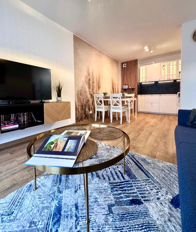 a living room with a glass coffee table and a kitchen at Apartament Perła Łagowa in Łagów