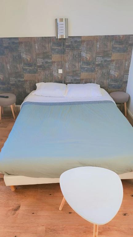 a large bed in a room with a white table at Hôtel 2 Gares in Nevers