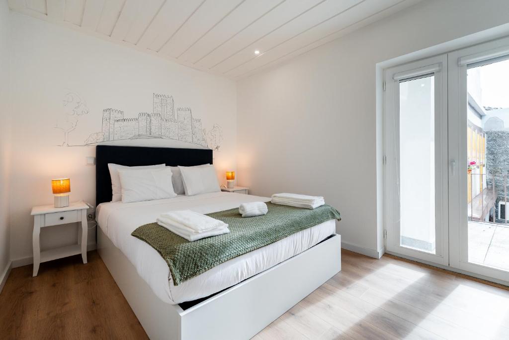 a white bedroom with a large bed and a window at Casa da Chica Apartamento Castelo 1 Esq in Guimarães