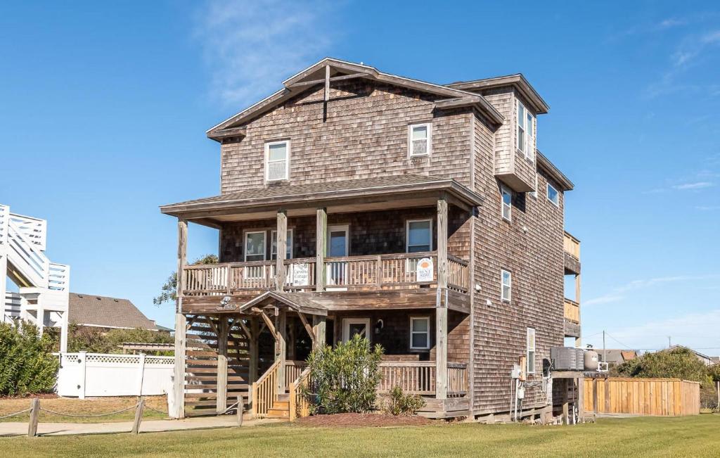 a large brick house with a porch and a balcony at Carolina Cottage - Kitty Hawk, Oceanside, Walk to Beach, Pool, Hot Tub, Pool Table in Kitty Hawk