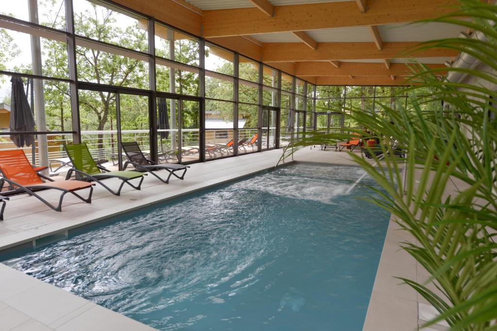 una piscina en una casa con sillas y ventanas en Résidence le Clos des Chênes, en Le Massegros