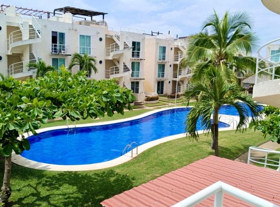 an apartment with a swimming pool and palm trees at Marina Diamante Plata D5 in Acapulco