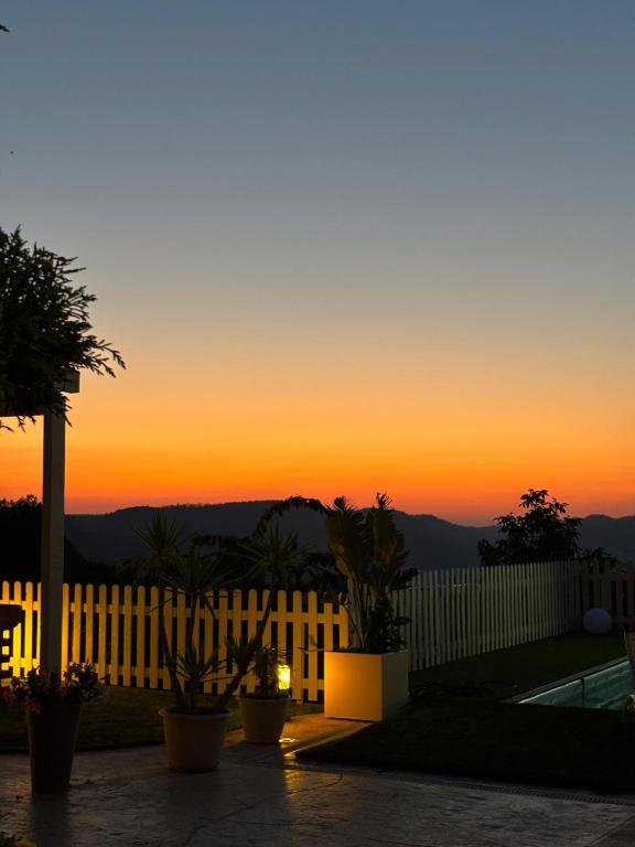 a sunset over a white fence with plants at Aidone Sunset House in Aidone