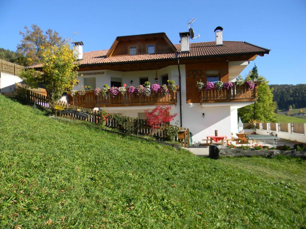 a house with flowers on the balconies on a hill at Unterweger Hof in Avelengo