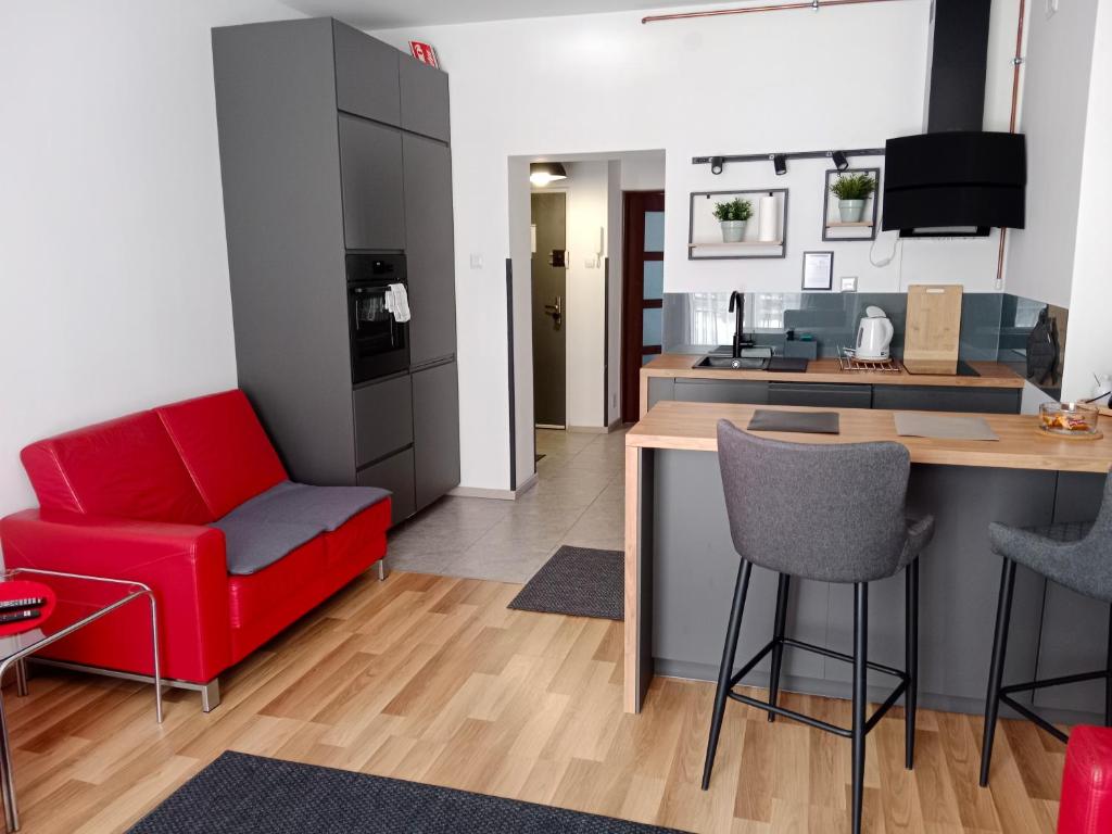 a living room with a red couch and a kitchen at Apartament - Elbląg in Elblag