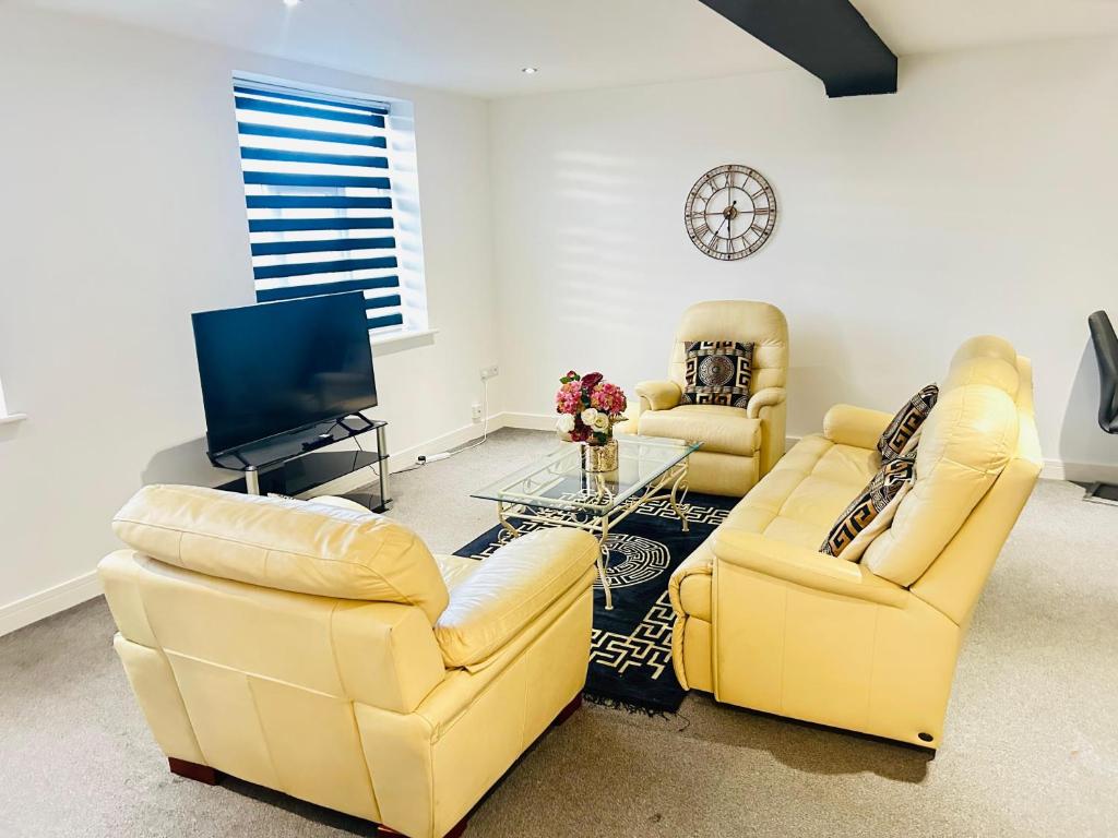 a living room with two yellow chairs and a tv at Doncaster 2 Bedroom Luxury Apartment in Doncaster