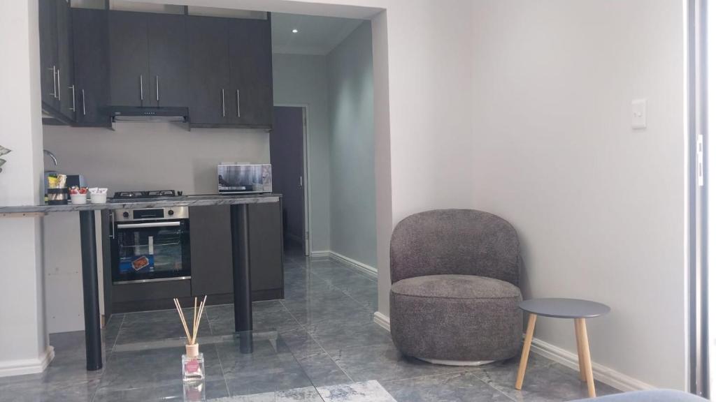 a kitchen with a chair and a table and a counter at B3 bnb House in Ravensmead