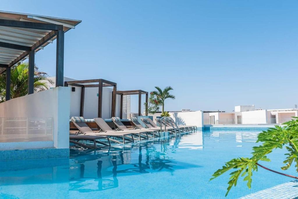 a row of lounge chairs on the side of a swimming pool at Luxury Condo in central location in Playa del Carmen