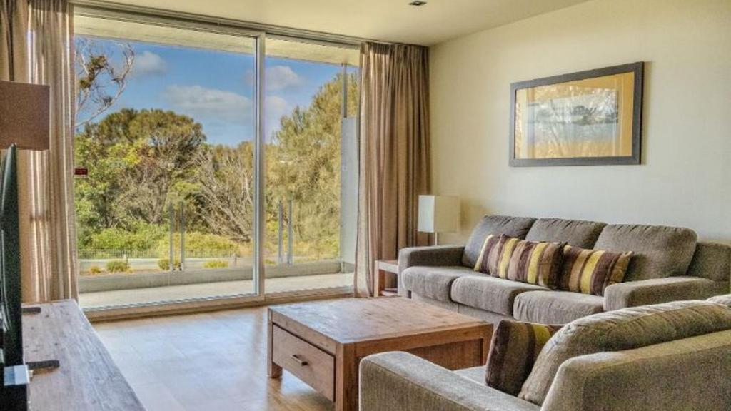 a living room with a couch and a large window at Resort Apartment 275 in Torquay