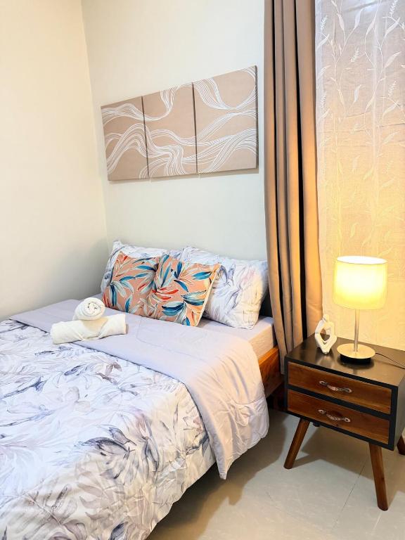 a bedroom with a bed and a table with a lamp at The Eastcape by Akeisha in Bacolod