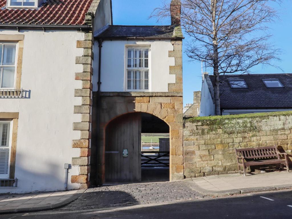 a building with a wooden door and a bench at Seafield Coach House in Alnwick