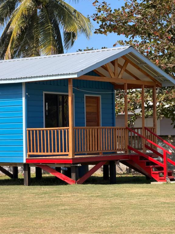 a blue tiny house with a porch and a deck at Sunshine Cabanas At Ocean View in Dangriga