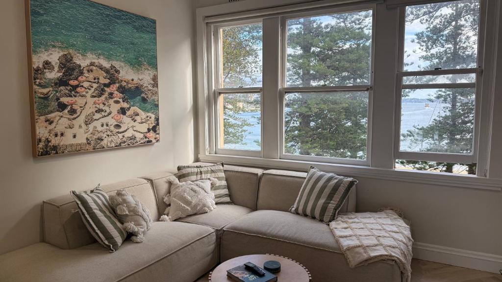 a living room with a couch and two windows at Manly Waterfront Apartment Harbourside in Sydney