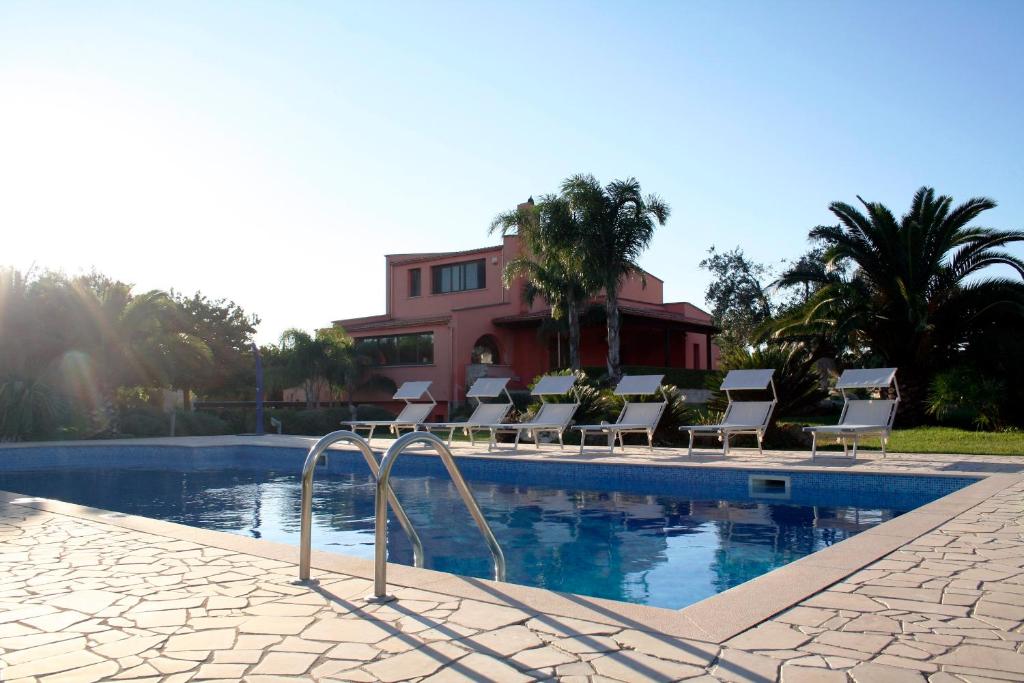 a swimming pool with lounge chairs next to a house at Pozzillo San Rocco in Arnesano