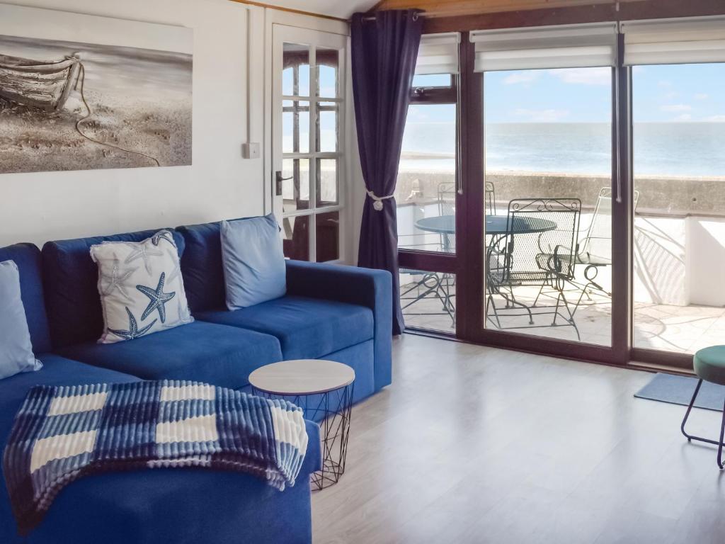a living room with a blue couch and a view of the ocean at Angie's Beachside House in Saint Osyth