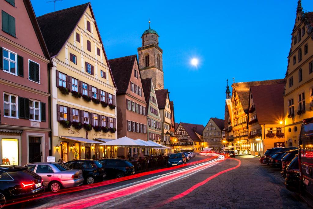 Una calle de la ciudad por la noche con coches aparcados en la calle en Meiser Altstadt Hotel, en Dinkelsbühl