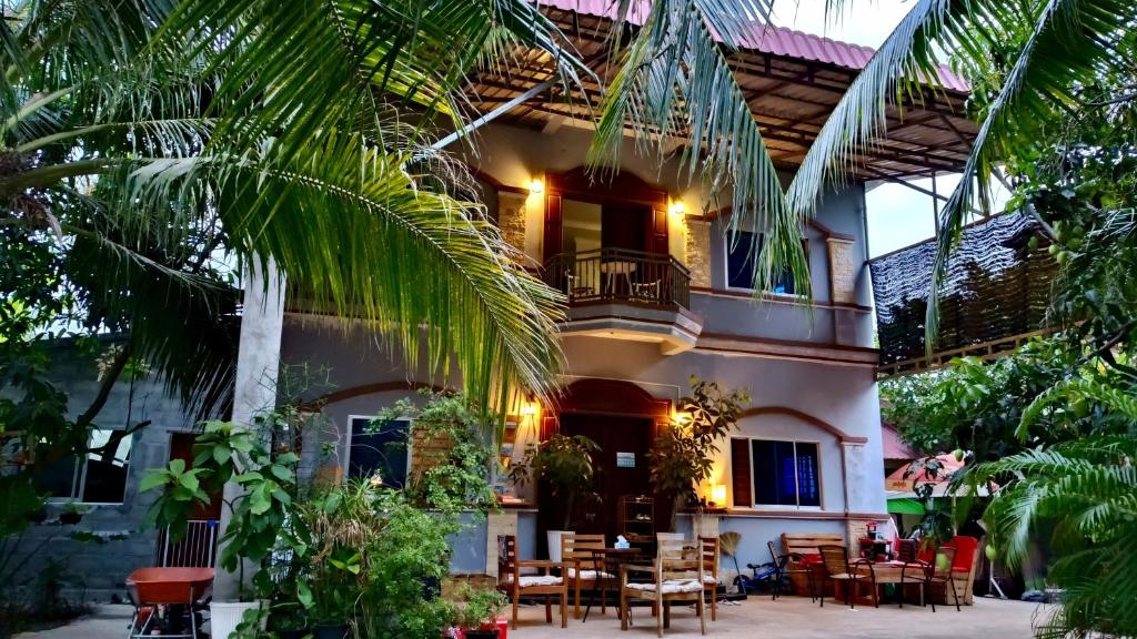 a house with a palm tree in front of it at La maison de Soriya - Homestay in Kampot