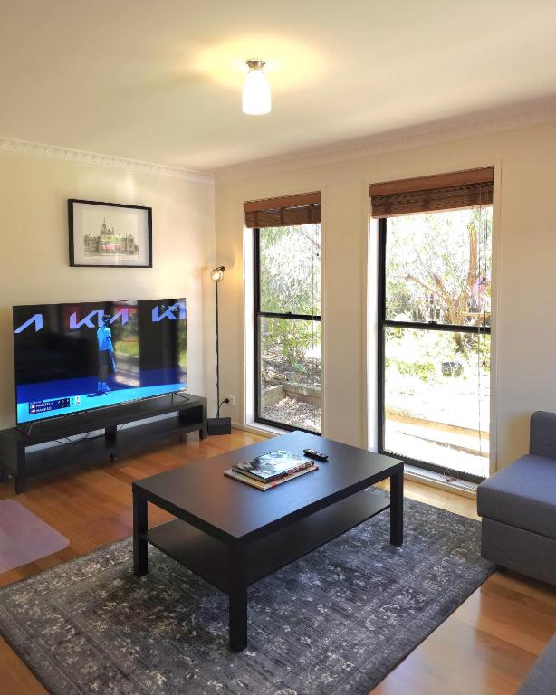 a living room with a coffee table and a flat screen tv at 2-Bedroom Townhouse Next to the Hospital in Bendigo