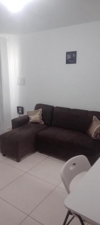 a living room with a brown couch and a chair at Casa condomínio in Maceió