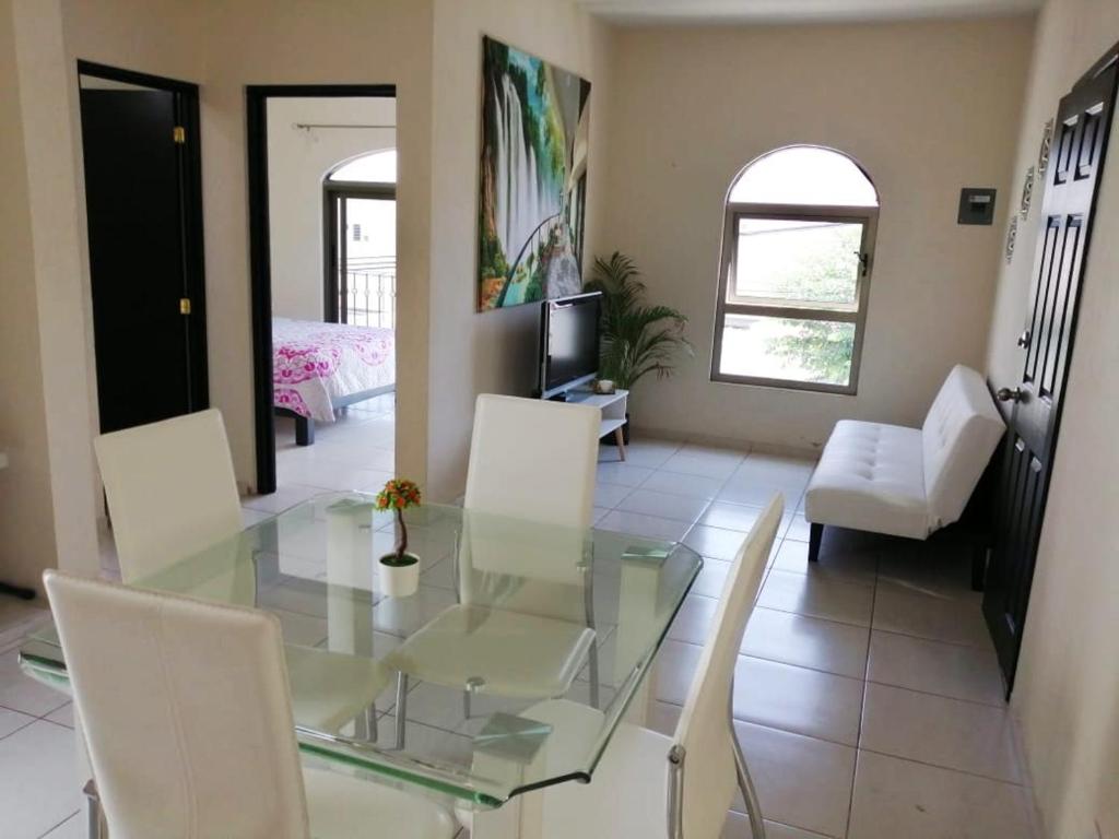 a dining room with a glass table and white chairs at VENECIA APARTMENT, Excellent Location in Tepic