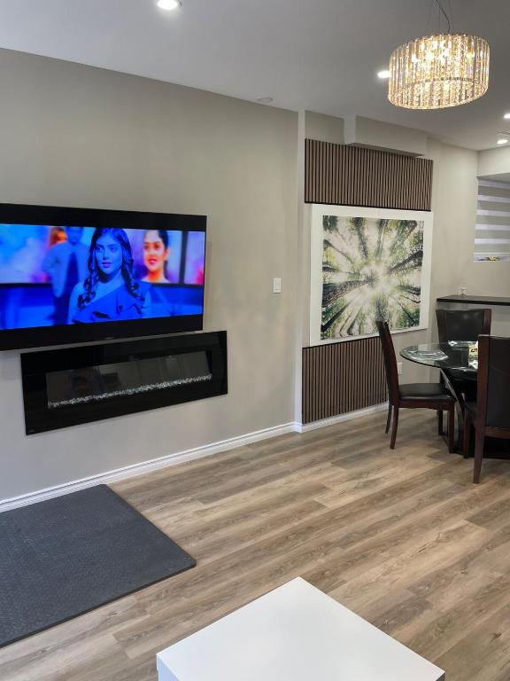 ein Wohnzimmer mit einem Fernseher an der Wand und einem Tisch in der Unterkunft New Basement Apartment unit sleeps 4 in Oakville
