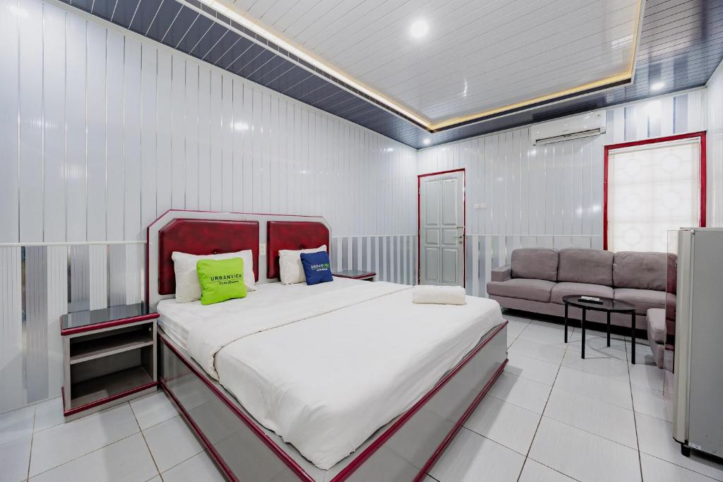 a bedroom with a large bed and a couch at Urbanview Hotel Executive Residence Semarang by RedDoorz in Candi