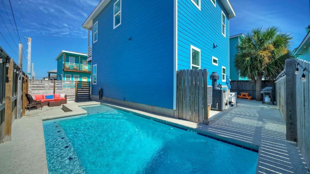 a blue building with a swimming pool next to a house at Ocean Devotion by AvantStay in Port Aransas
