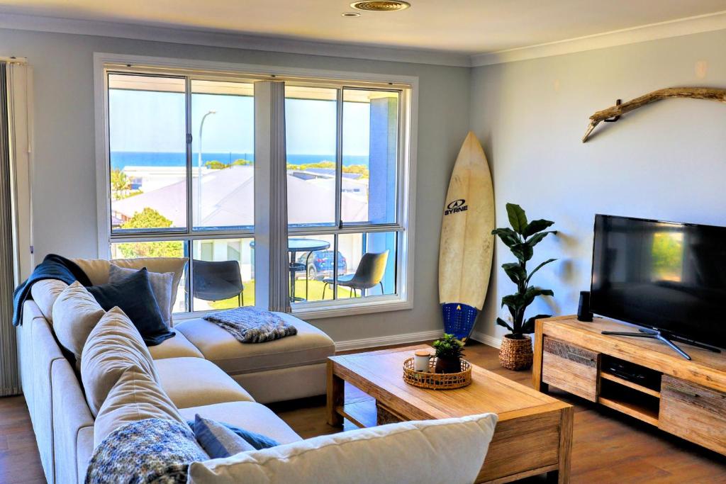 a living room with a couch and a surfboard at Diamond Beach Getaway - Diamond Beach in Diamond Beach