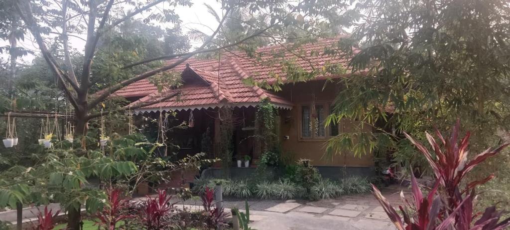 a house with a red roof and a garden at Puthooram Veedu in Chakkarakkal