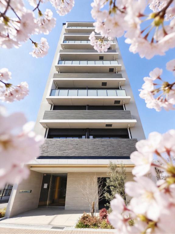 a high rise building with pinkakuraakura flowers in the foreground at AYA Residence大阪城公園 Osaka Castle JR Morinomiya 徒歩5min in Osaka