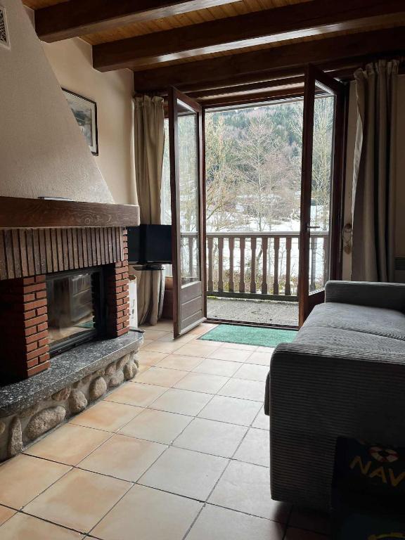 a living room with a fireplace and a bed at appartement le petit chalet sauna in La Bresse