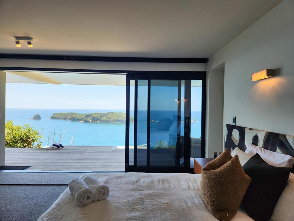 a bedroom with a bed with a view of the ocean at Dreamtime Hahei in Hahei