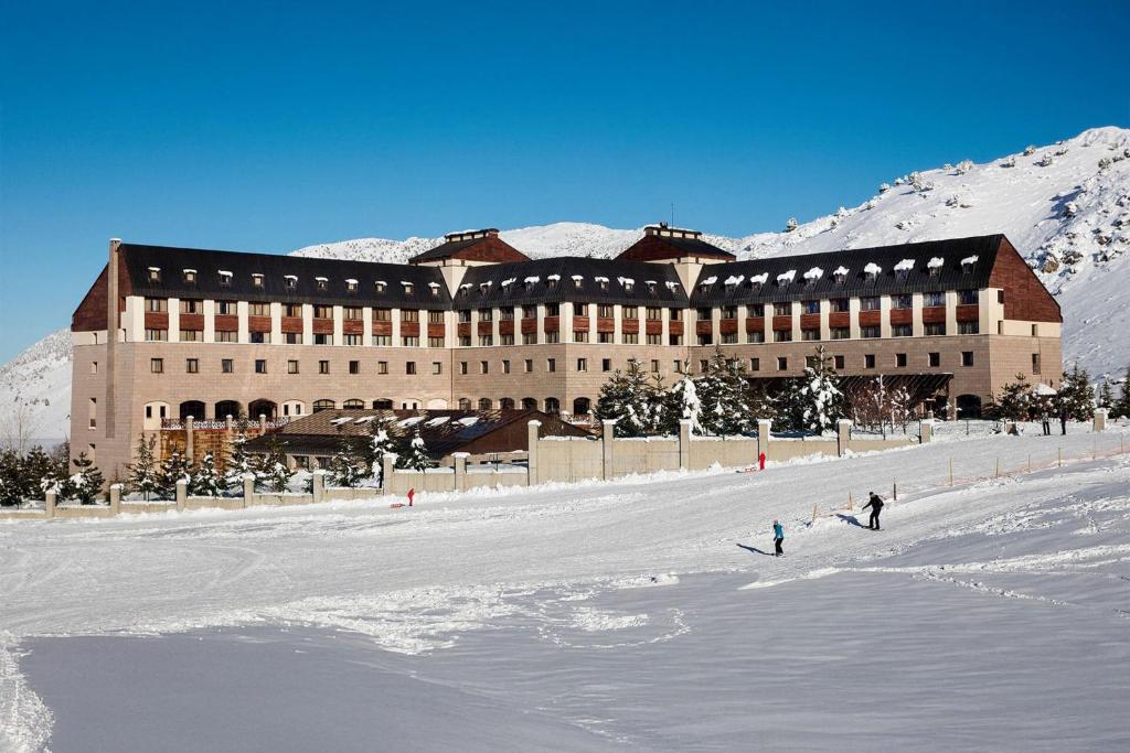 a large building in the snow with people in front of it at Barida Hotels Davraz in Cobanisa