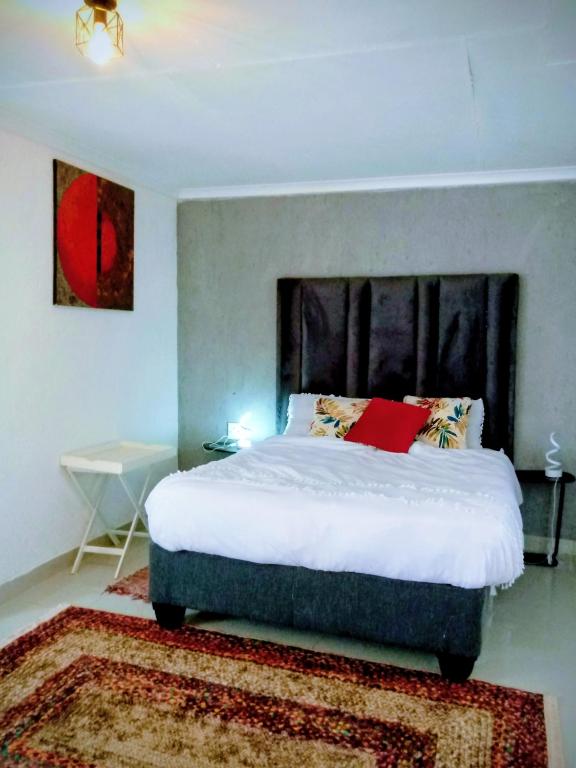 ein Schlafzimmer mit einem großen Bett und einem roten Kissen in der Unterkunft GenAyah Hotel & Safari in Mtimba
