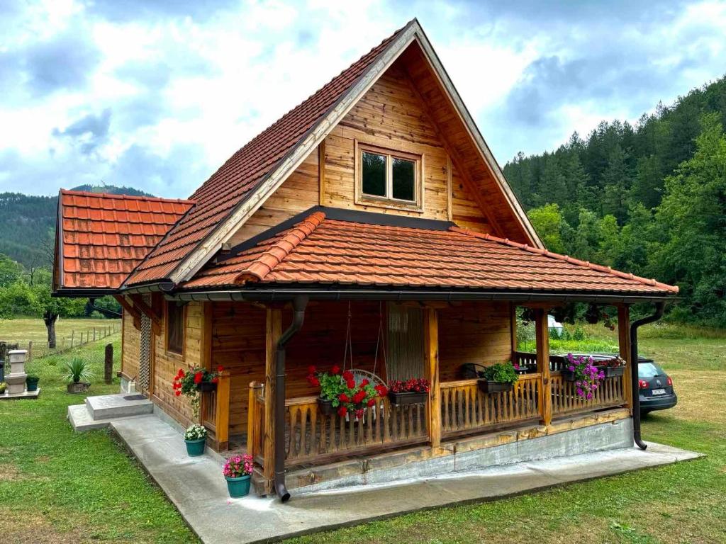 a log cabin with a porch and a roof at Apartmani D&S in Mokra Gora