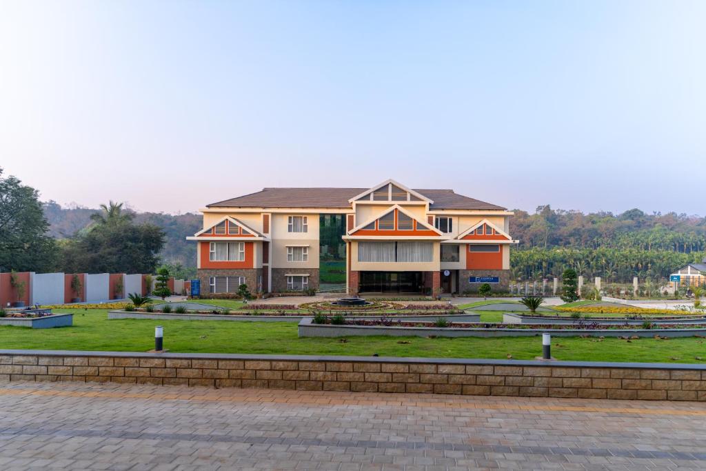 a large house on a green field with a driveway at Omkar Jungle Resort & Spa, Sirsi in Islūr