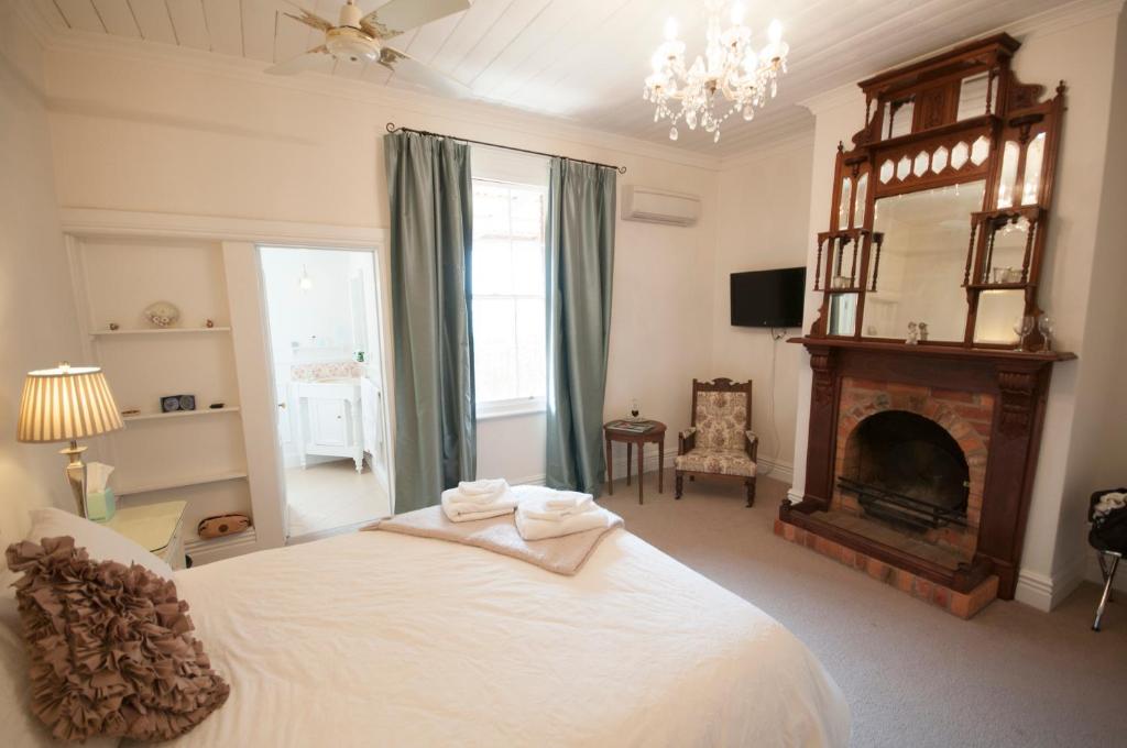 a bedroom with a white bed and a fireplace at The Graces Beechworth in Beechworth