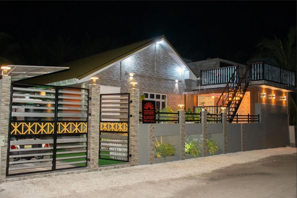 a house with a fence in front of it at night at Sunset Private Villa in Bandara
