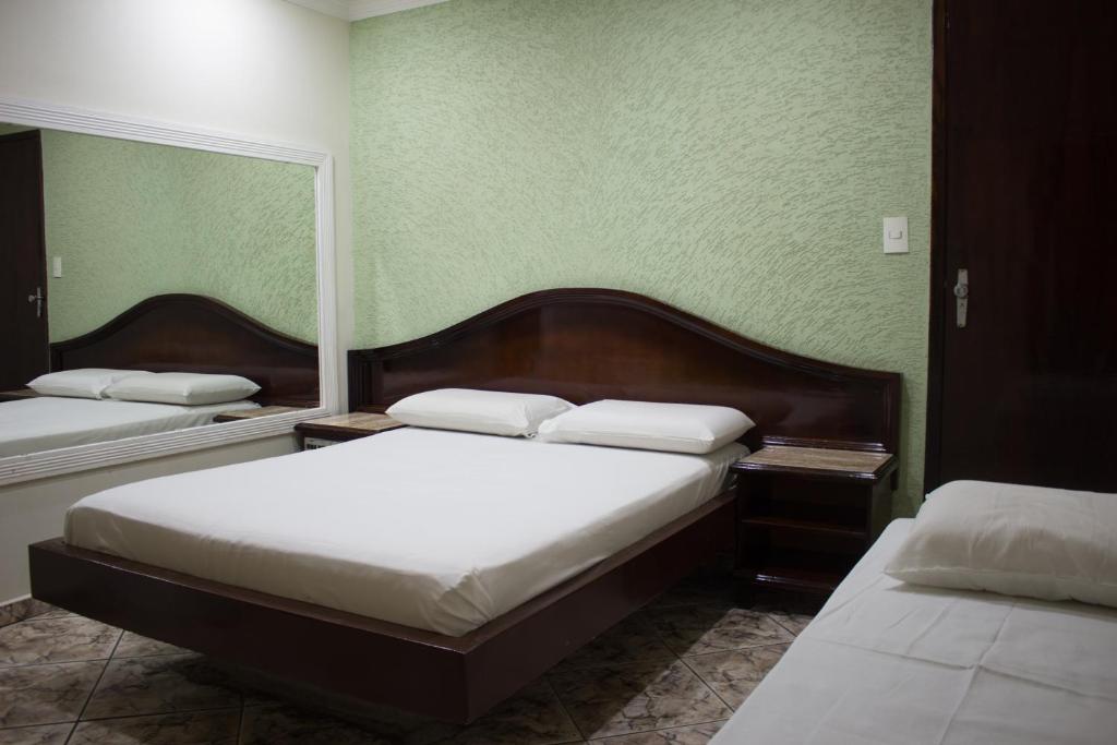 2 camas en una habitación con paredes verdes en Hotel Valadares en Brasilia