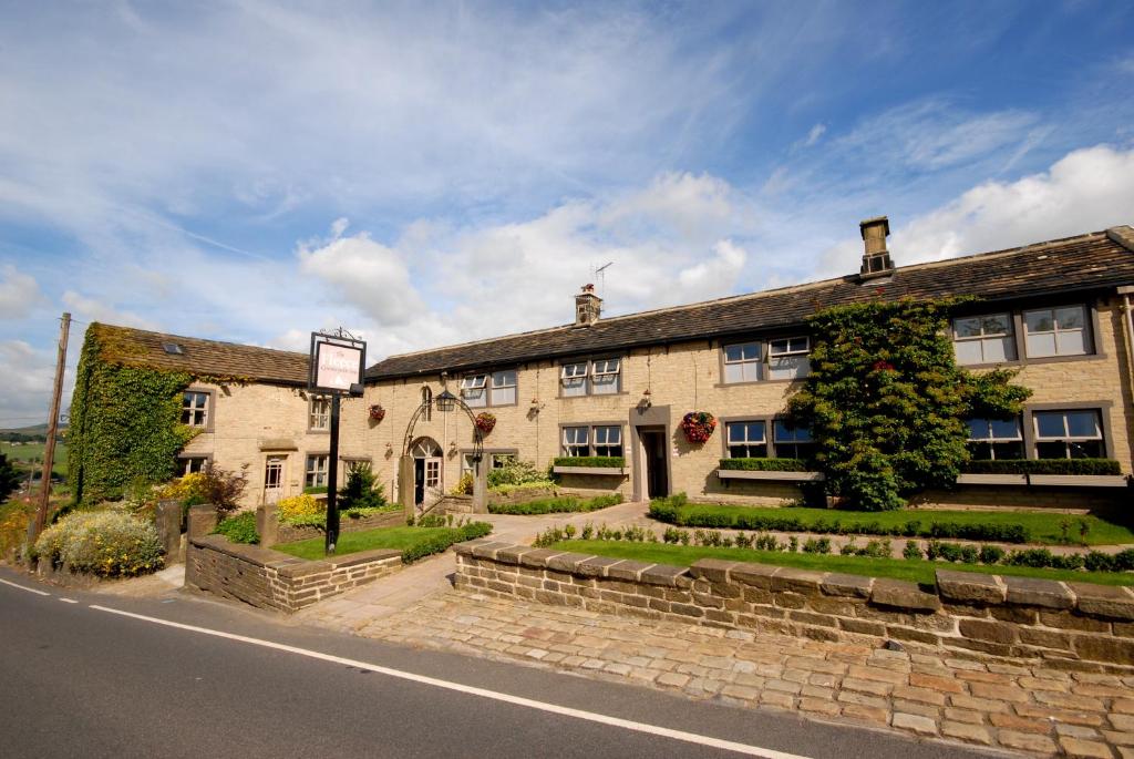 a large stone building on the side of a street at The Fleece Inn at Barkisland in Ripponden