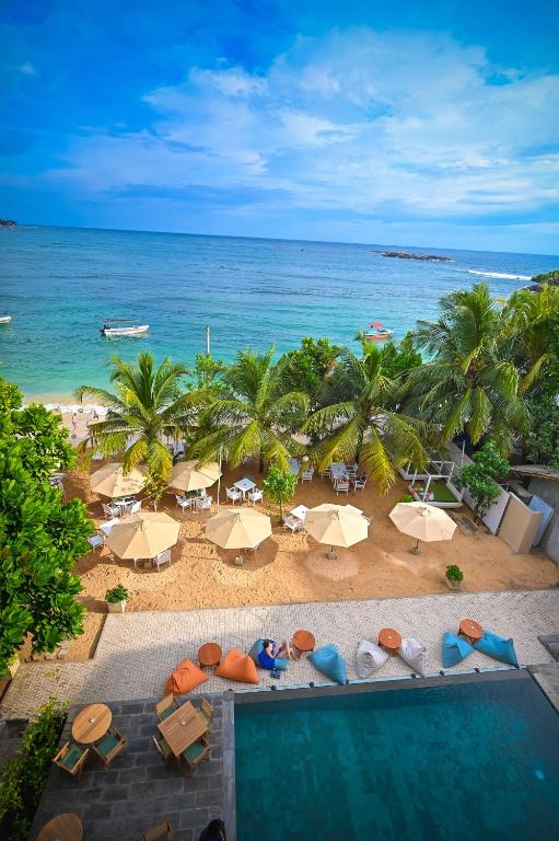 an aerial view of a beach with umbrellas and the ocean at Kingfisher Beach in Unawatuna
