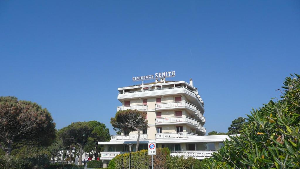 a white building with a blue sign on top of it at Residence Zenith - Agenzia Cocal in Caorle