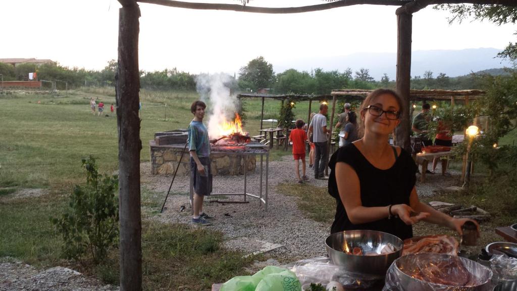 a woman preparing food in front of a fire at Agricampeggio Madonna di Pogi in Bucine