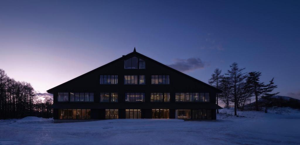 a large building with windows in the snow at Lomä Central Peaks in Shinano