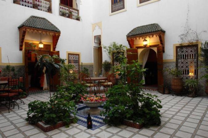 un patio con mesas, sillas y plantas en un edificio en Riad Dalia, en Marrakech