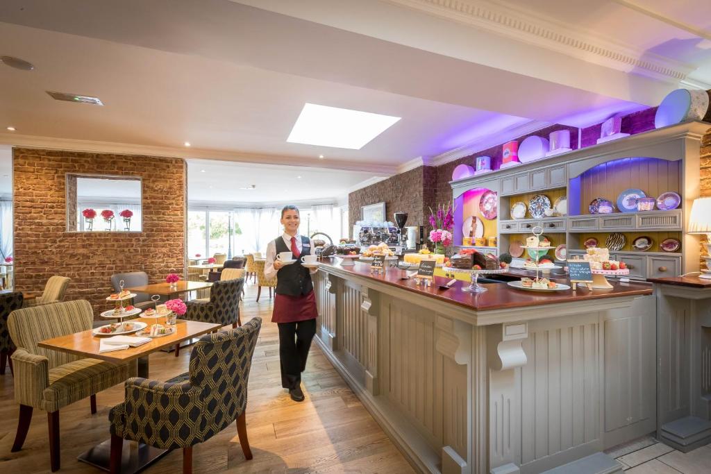 a woman standing at a bar in a restaurant at Springhill Hotel Kilkenny in Kilkenny