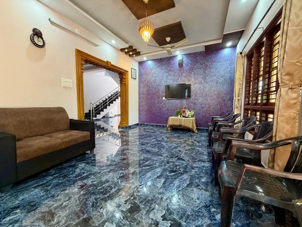 a living room with a couch and chairs and a tv at Laksh Nivas Fields Stay in Udupi