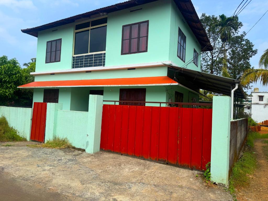 a house with a red fence in front of it at Cosy Kalpetta Villa in Kalpetta